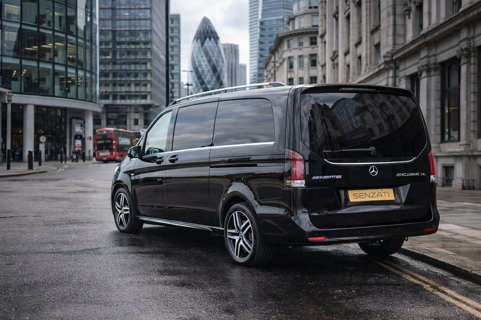 Black Mercedes-Benz van parked on a city street with modern buildings and a double-decker bus in the background.