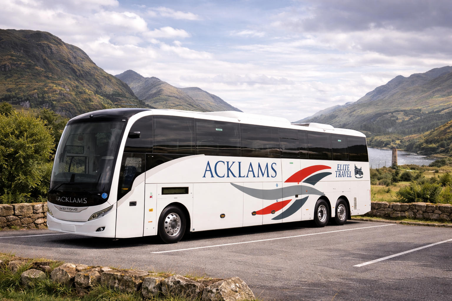 White tour bus with 'ACKLAMS' printed on the side, parked on a scenic mountain landscape with water, mountains, and cloudy sky in background.