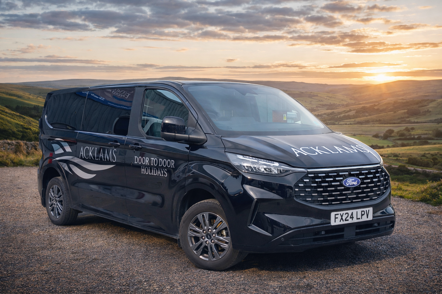 Black Ford Transit van with company branding on the side, parked on a gravel surface during sunset, with green rolling hills in the background.