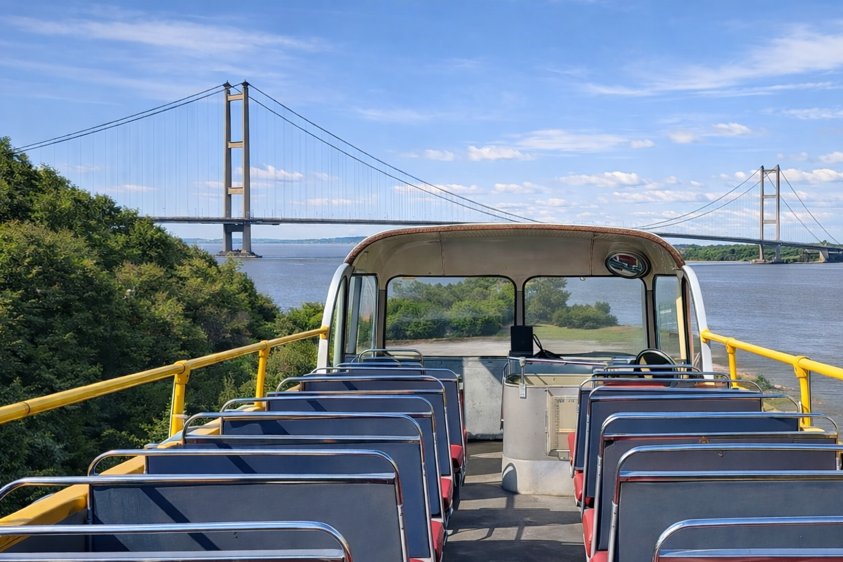 View from a boat with multiple empty seats, a yellow railing, overlooking a body of water, with a large suspension bridge in the background under a partly cloudy sky.