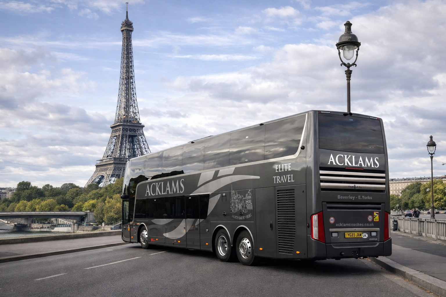 A double-decker coach bus branded with 'ACKLAMS' parked on a bridge in Paris with the Eiffel Tower in the background, under a partly cloudy sky.