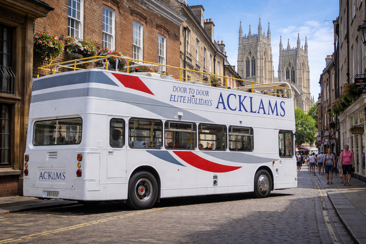 A white double-decker bus with the words 'ACKAMS' and 'Door to Door Elite Holidays' on its side, parked on a cobblestone street amidst historic brick buildings and a cathedral in the background, with pedestrians walking nearby on a sunny day.