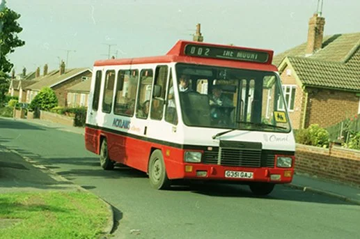 A red and white city bus on a residential street.