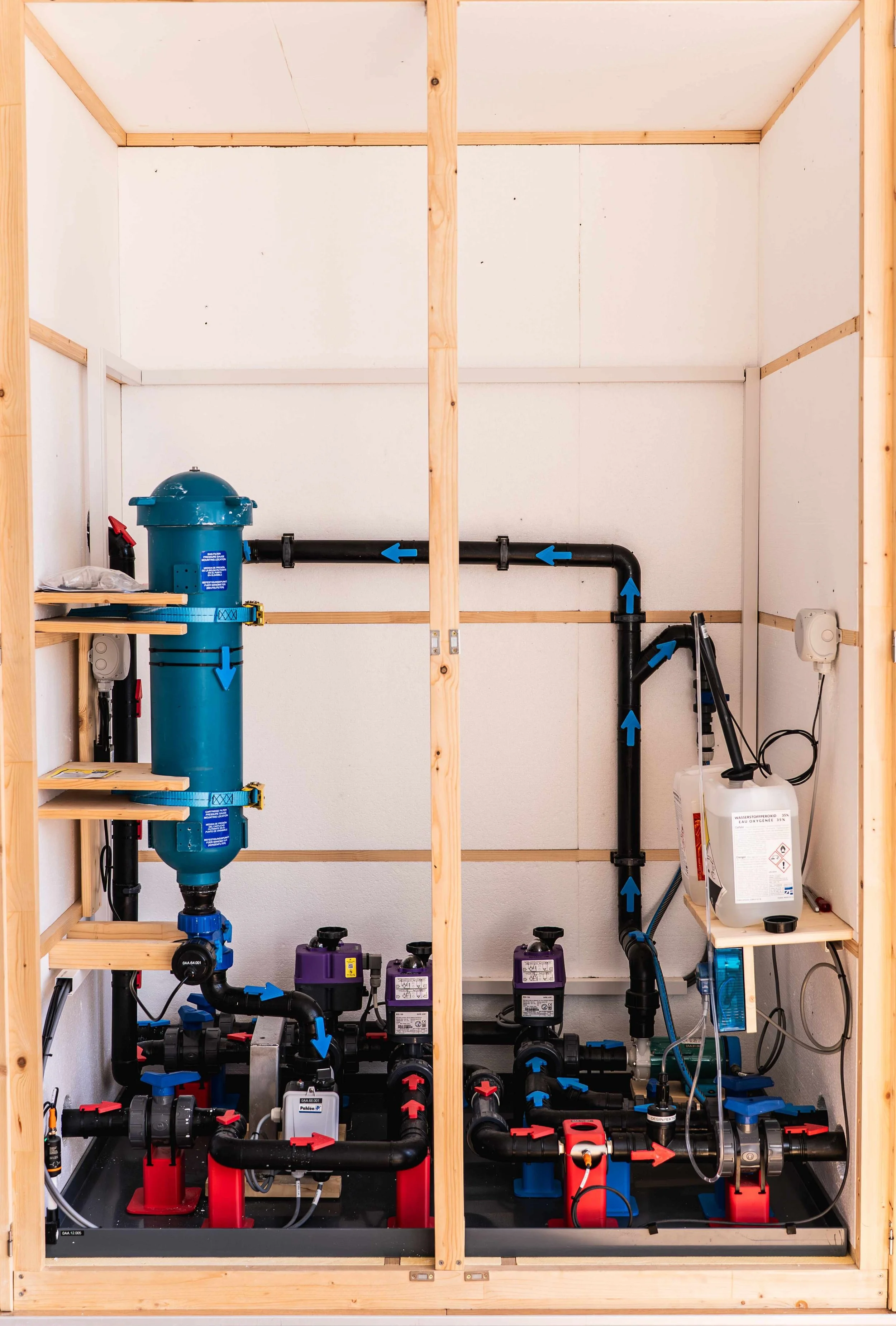 Ein Wasserfiltersystem mit Rohrleitungen, Pumpen und einem Reiniger, in einem Holzregal installiert, für die Wasseraufbereitung des Floating Tanks Rea Float