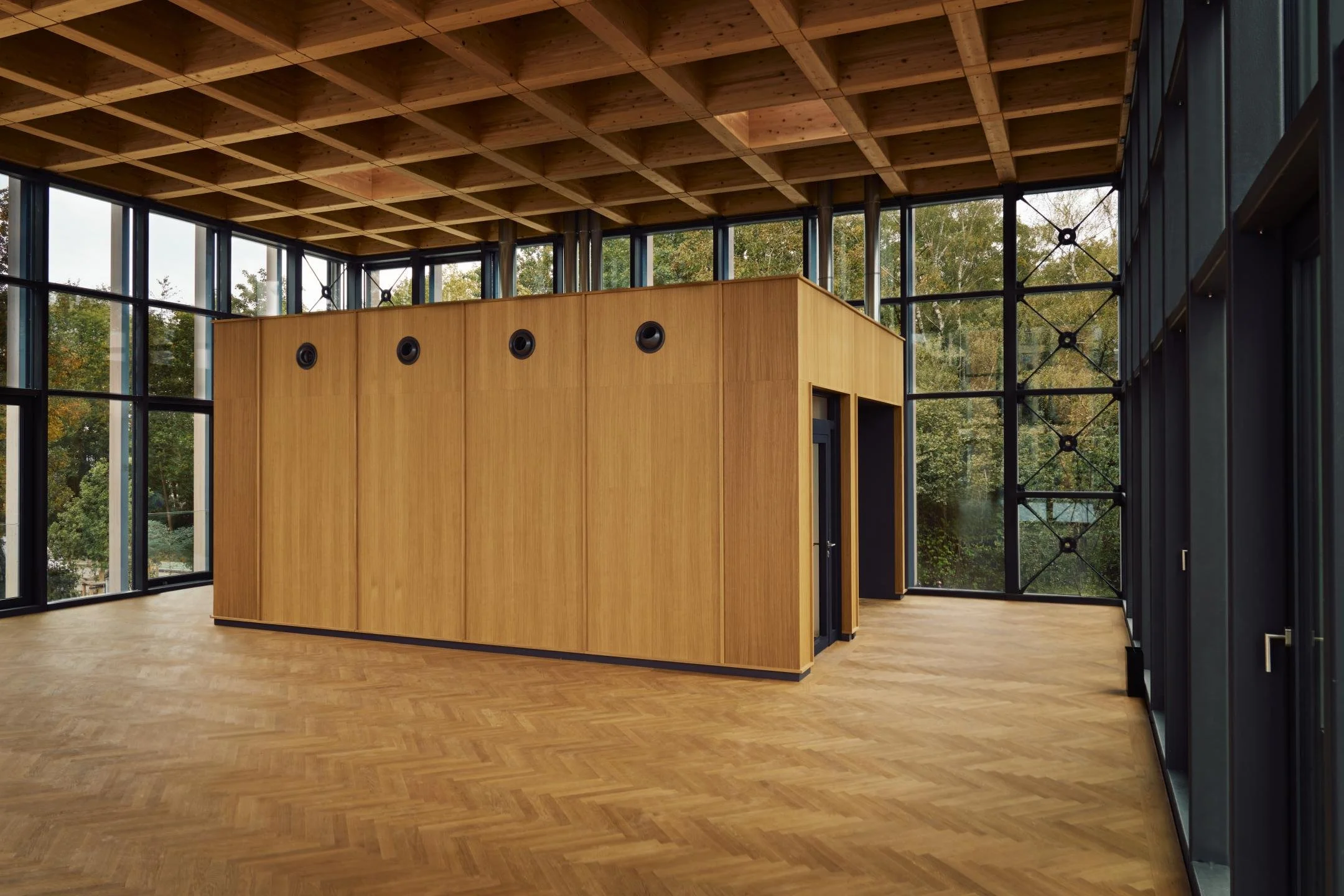 Innenraum eines modernen Gebäudes mit großen Fensterflächen, Holzverkleidung und Holzfußboden, Blick auf einen essentiellen Raum mit Raumtrennwand