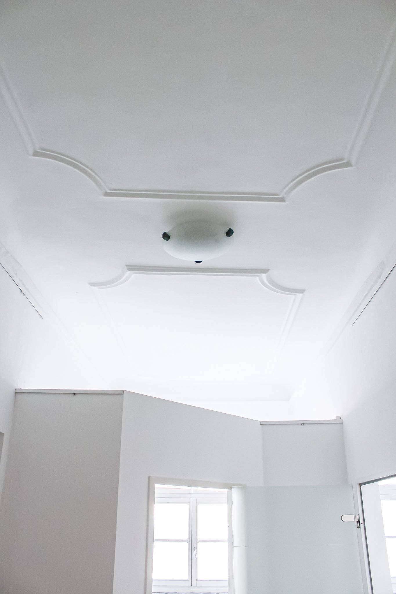 Hell erleuchteter Raum mit weißer Decke, Fenster und Türen, helles Licht durch die Fenster, moderne Inneneinrichtung.