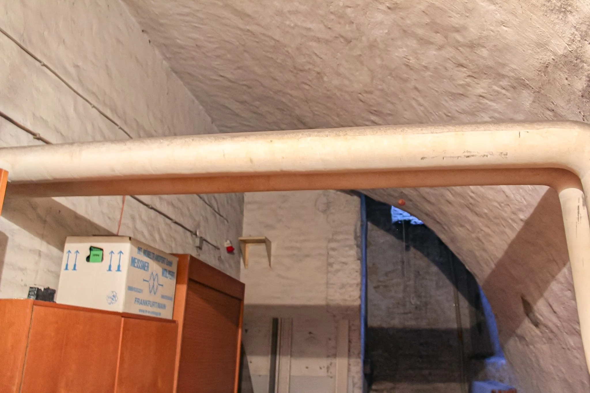 Blick auf einen Raum mit Bau- oder Renovierungsarbeiten, sichtbare Rohre, Möbel und Kartons.