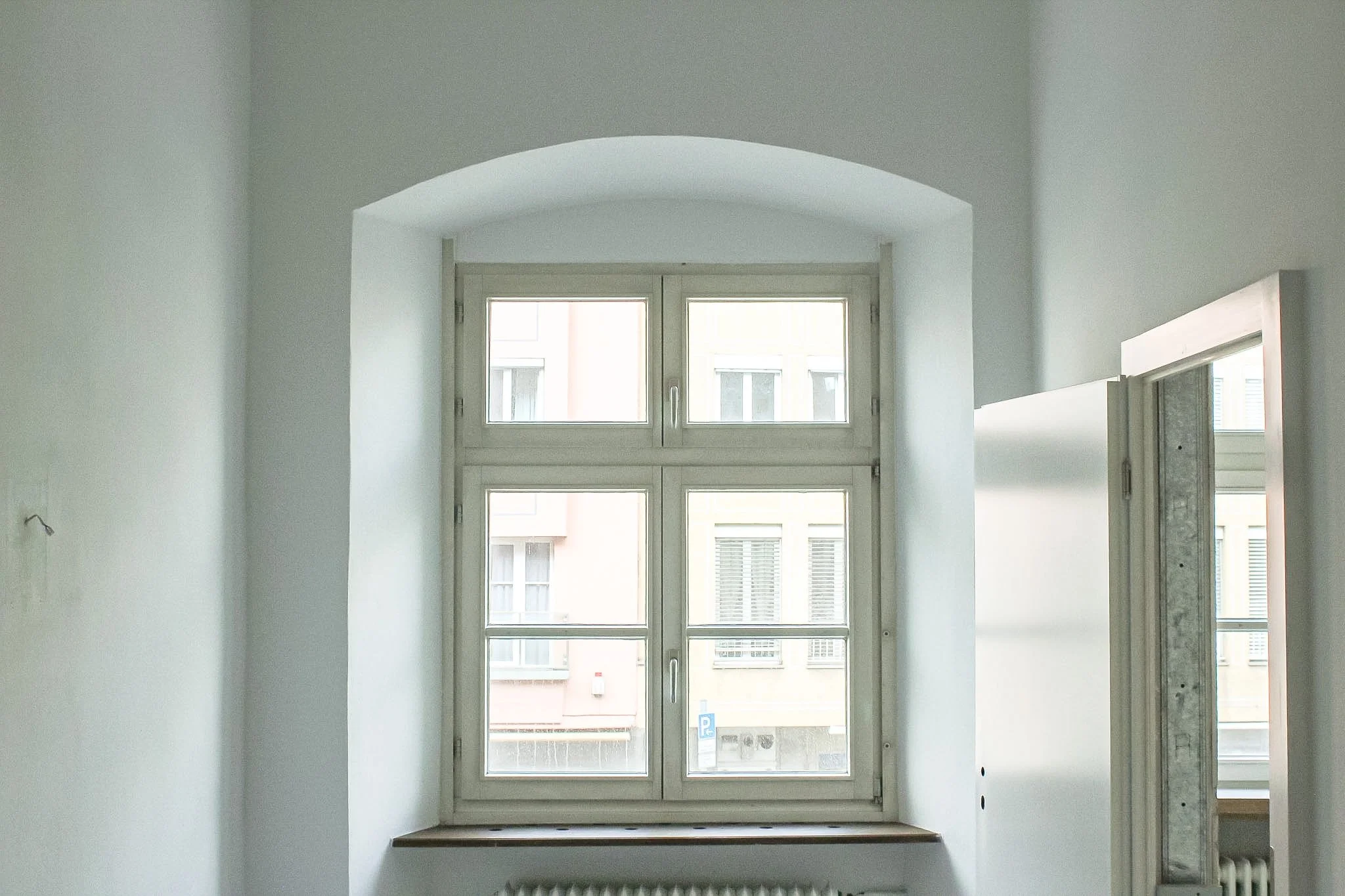 Innenansicht eines Zimmers mit einer großen Fensterfront in der Wandmitte.