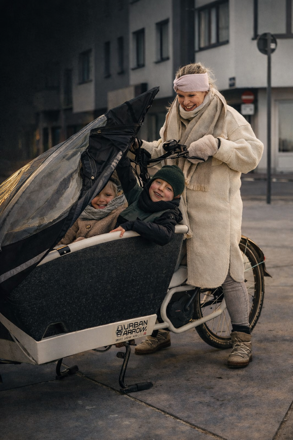 Vrolijke vrouw met twee kinderen in een fiets met een kinderzitje op straat in de avond.