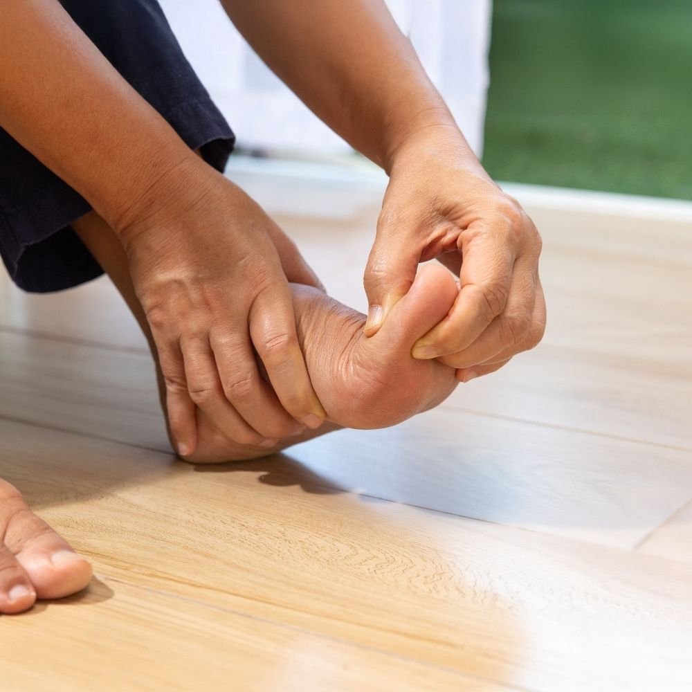 Close-up of a person stretching their toes with their hands, representing foot pain and podiatry treatment