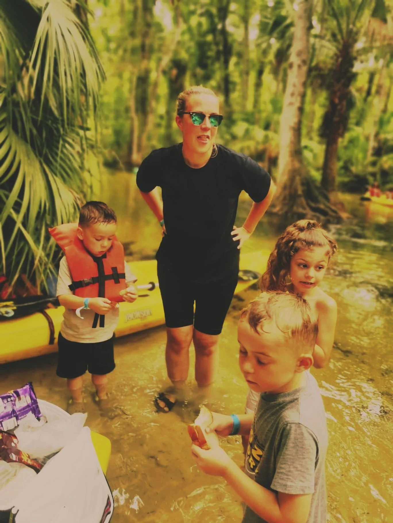 Mother and children enjoying time together outdoors in shallow water.