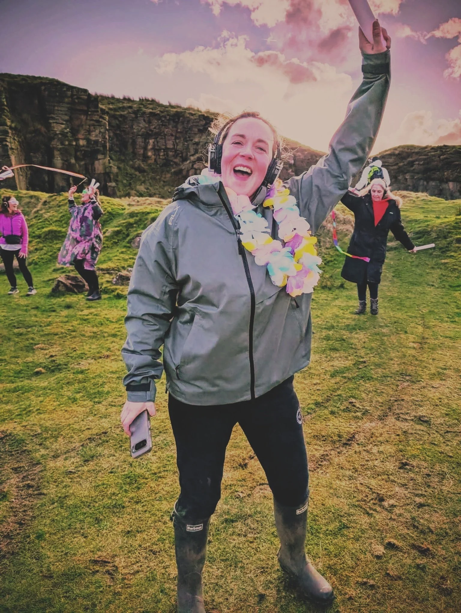 Smiling woman celebrating outdoors with friends in the background.