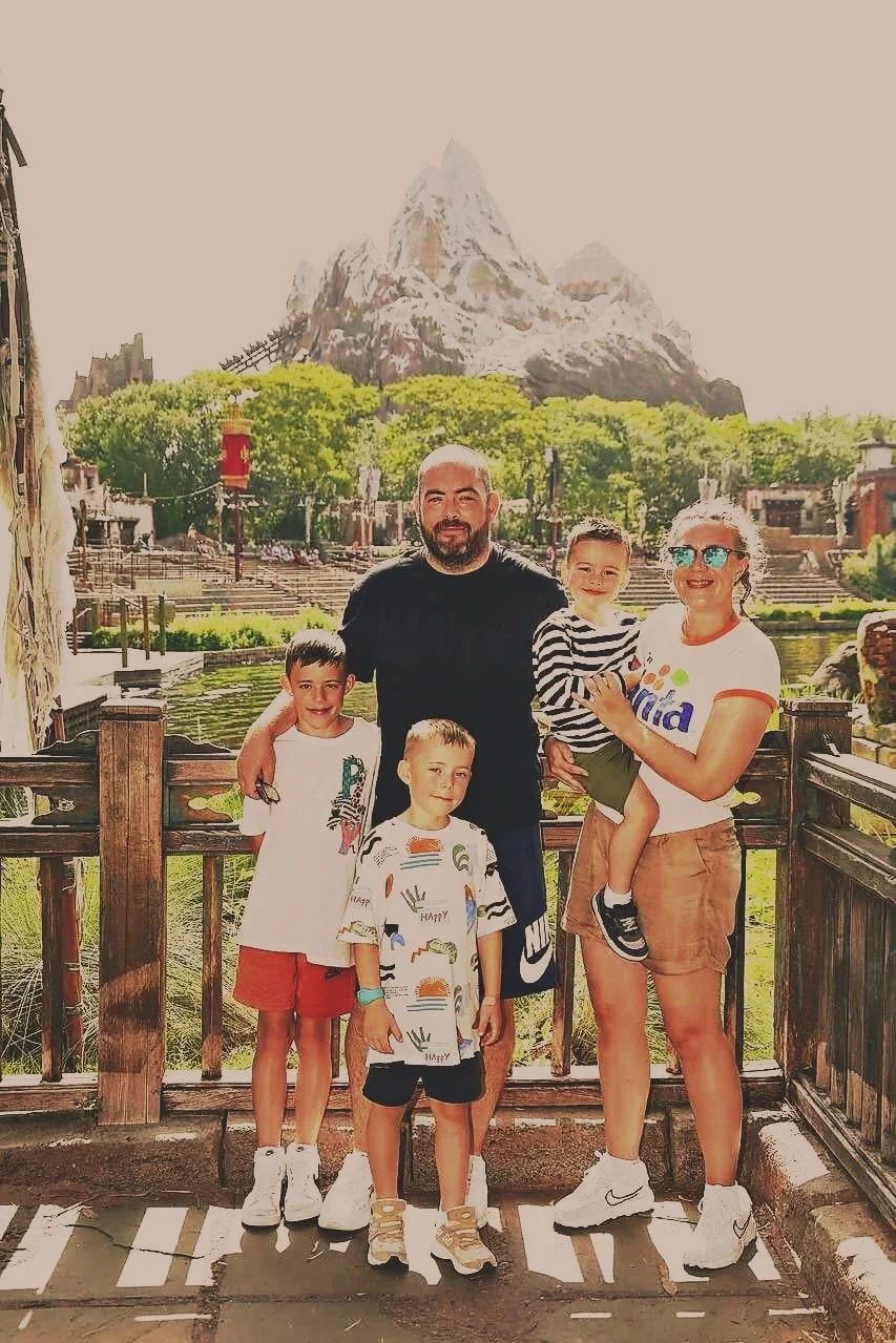 Family of five standing together outdoors with scenic mountain views.