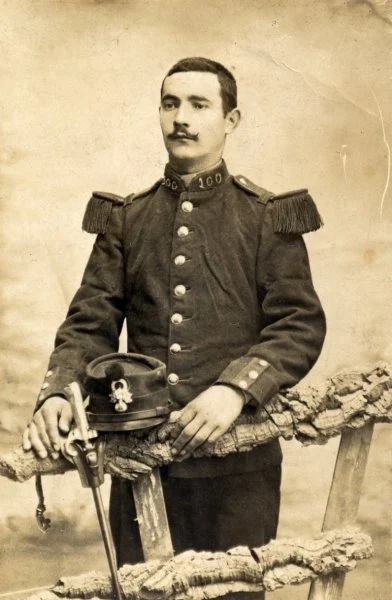 Portrait d'un officier en uniforme militaire avec un casque posé sur une table en bois.