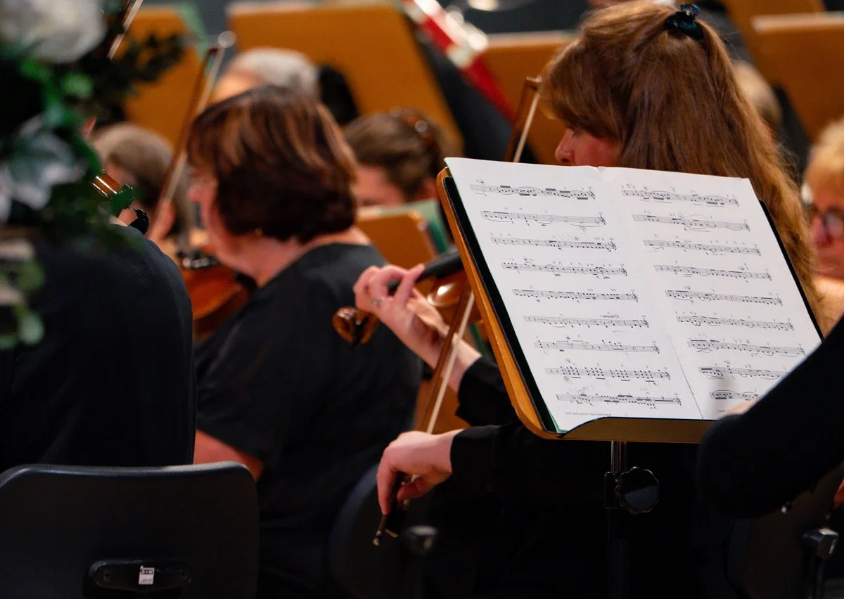Symphoniekonzert Markenpräsentation - Detailaufnahme Notenständer mit Notenblättern, Streicher unscharf im Hintergrund - Markenfotografie Culet