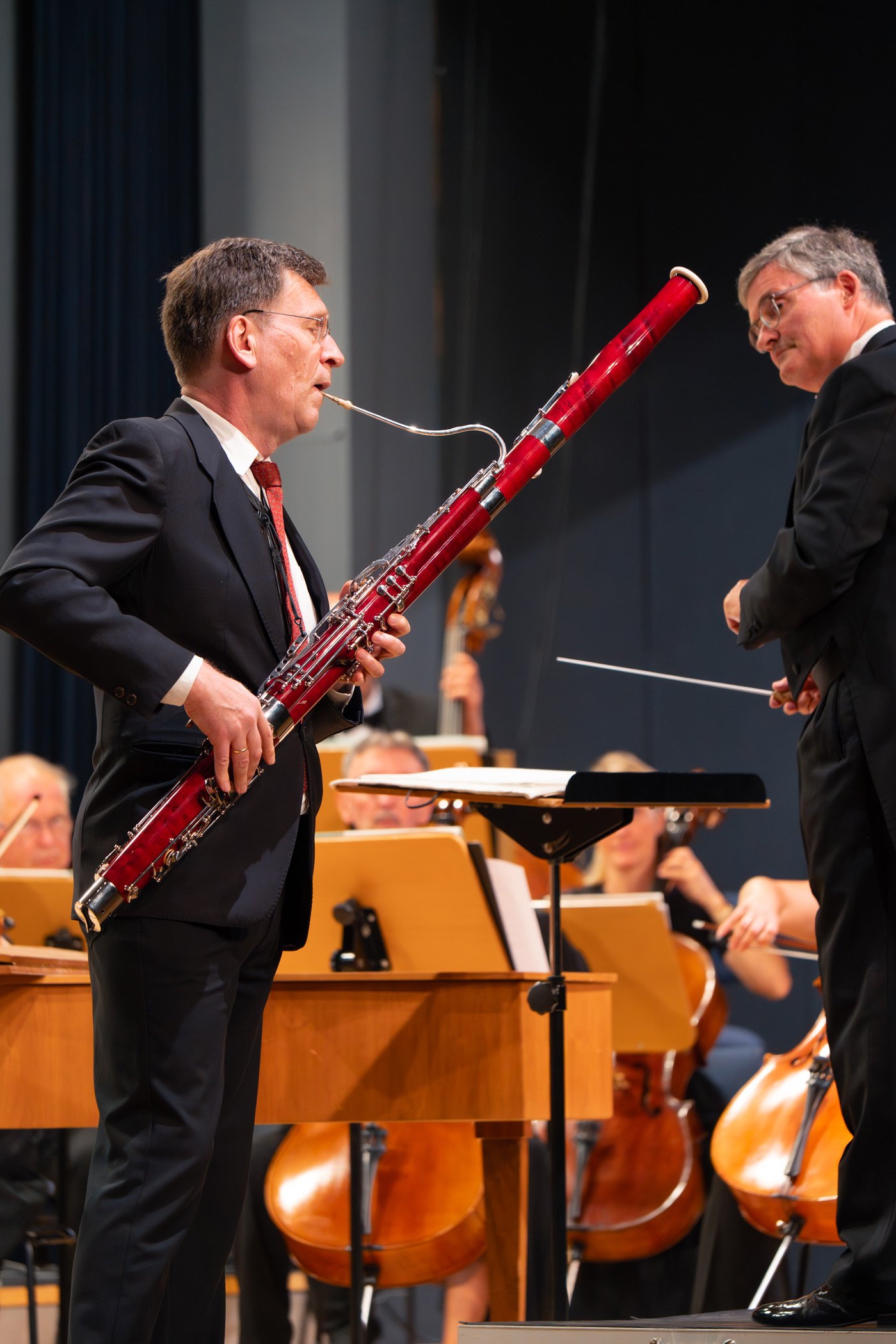 Symphoniekonzert Markenpräsentation - Musiker mit rotem Fagott im Vordergrund, Dirigent und Orchester im Hintergrund - Markenfotografie Culet