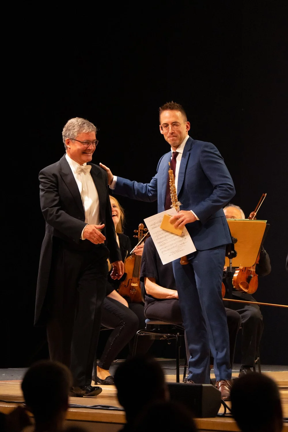 Symphoniekonzert Markenpräsentation - Klarinettist betritt die Bühne und begrüßt lächelnd den Dirigenten - Markenfotografie Culet