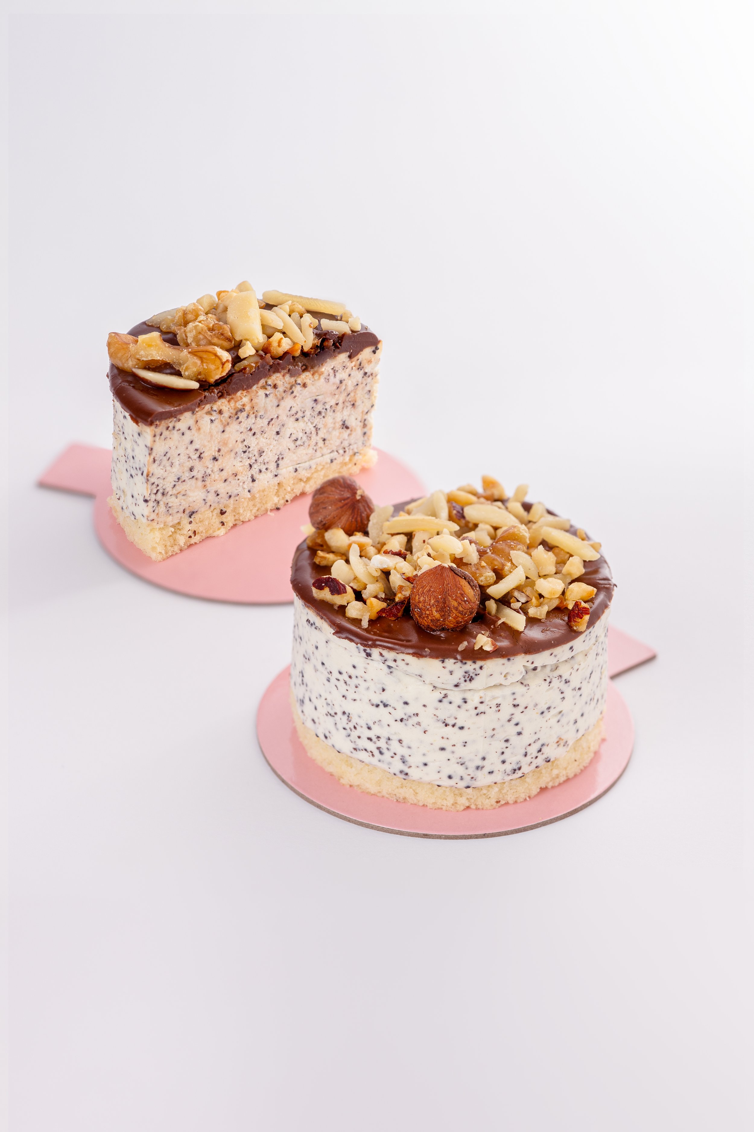 Zwei kleine Kuchen mit Schokoladenüberzug, gehackt Nüssen und Haselnüssen auf weißem Hintergrund