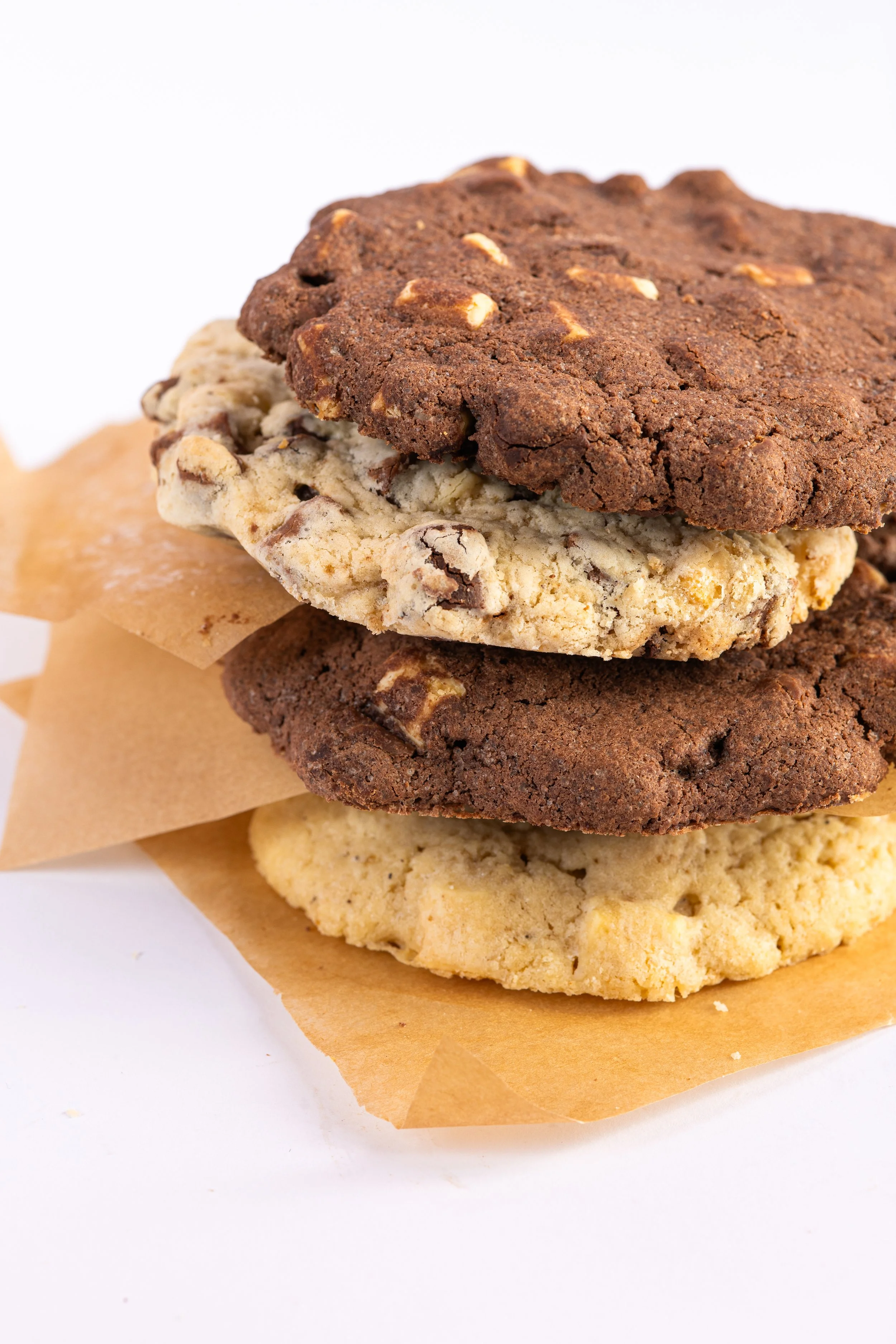 Vier Cookies verschiedener Sorten, übereinander gestapelt auf Backpapier