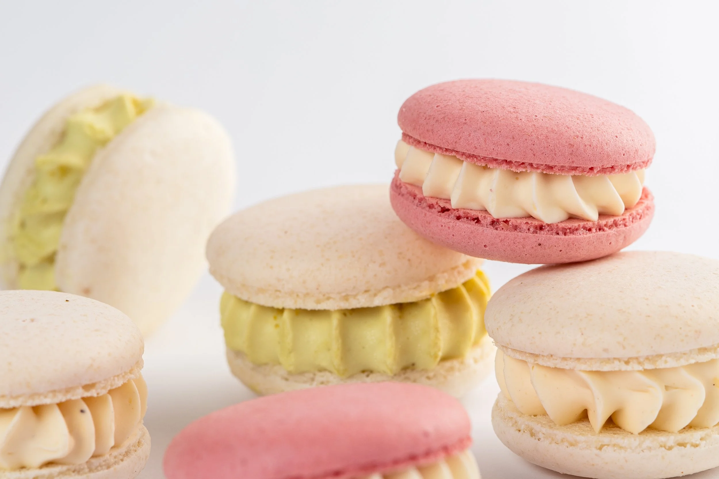 Verschiedene bunte Makronen mit Cremefüllung auf weißem Hintergrund.