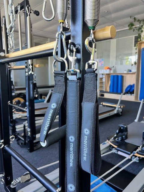Clinical Pilates equipment in a wellness studio, including resistance bands and a reformer machine.