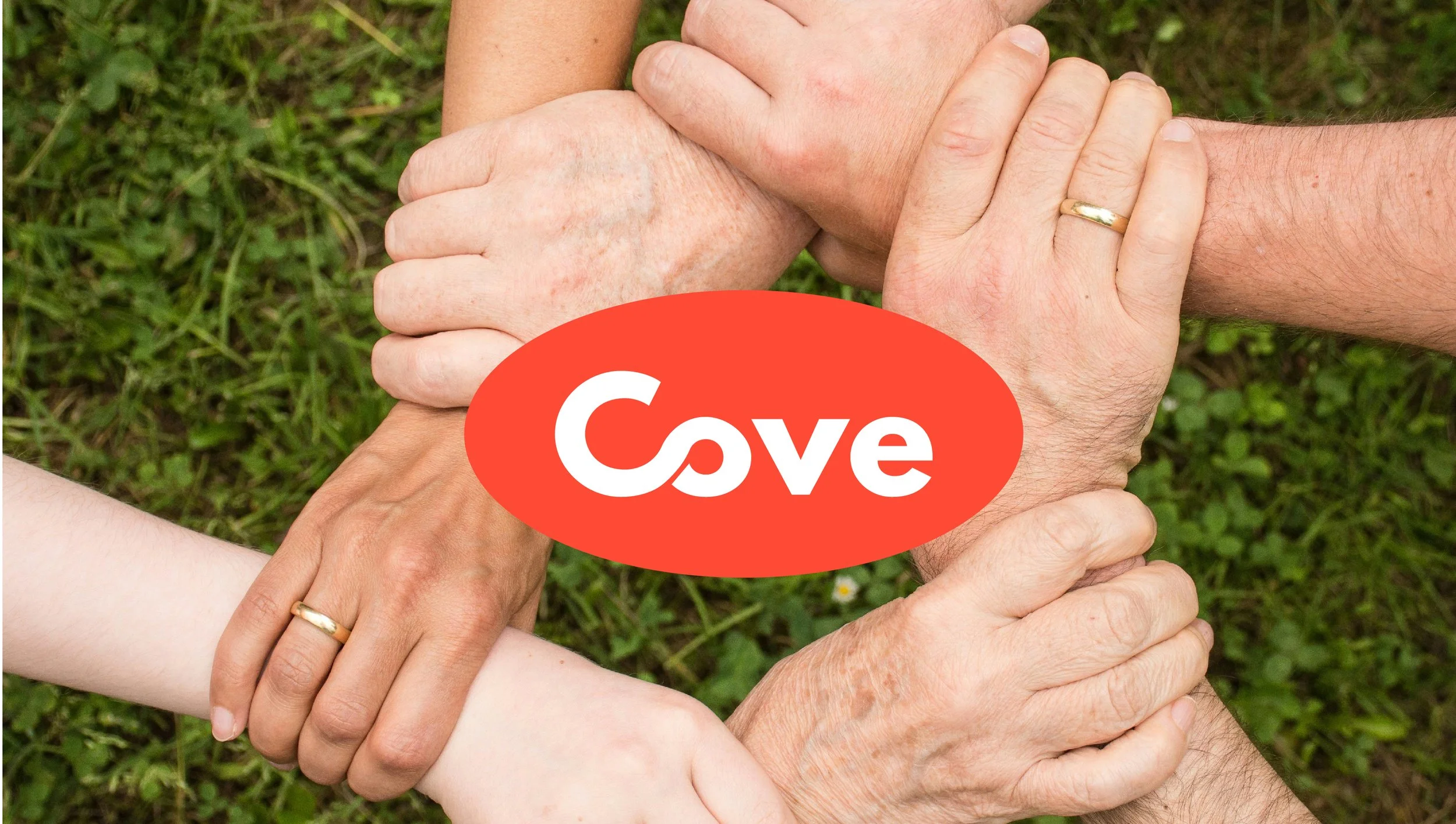 Multiple hands of different ages and skin tones intertwined in a circle on grass, with a red oval logo that says "Cove" in white text overlaying the center of the circle.