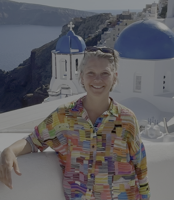 Kvinde smilende foran den hvide kirke med blå kuppel i Santorini, Grækenland.