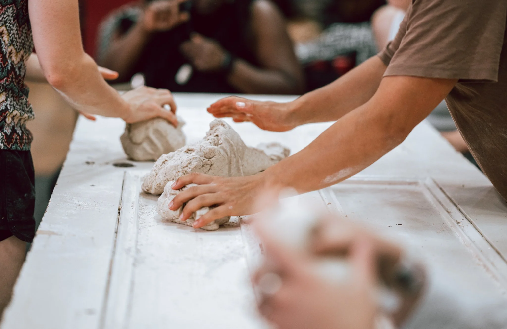 Women kneading dough on a table.