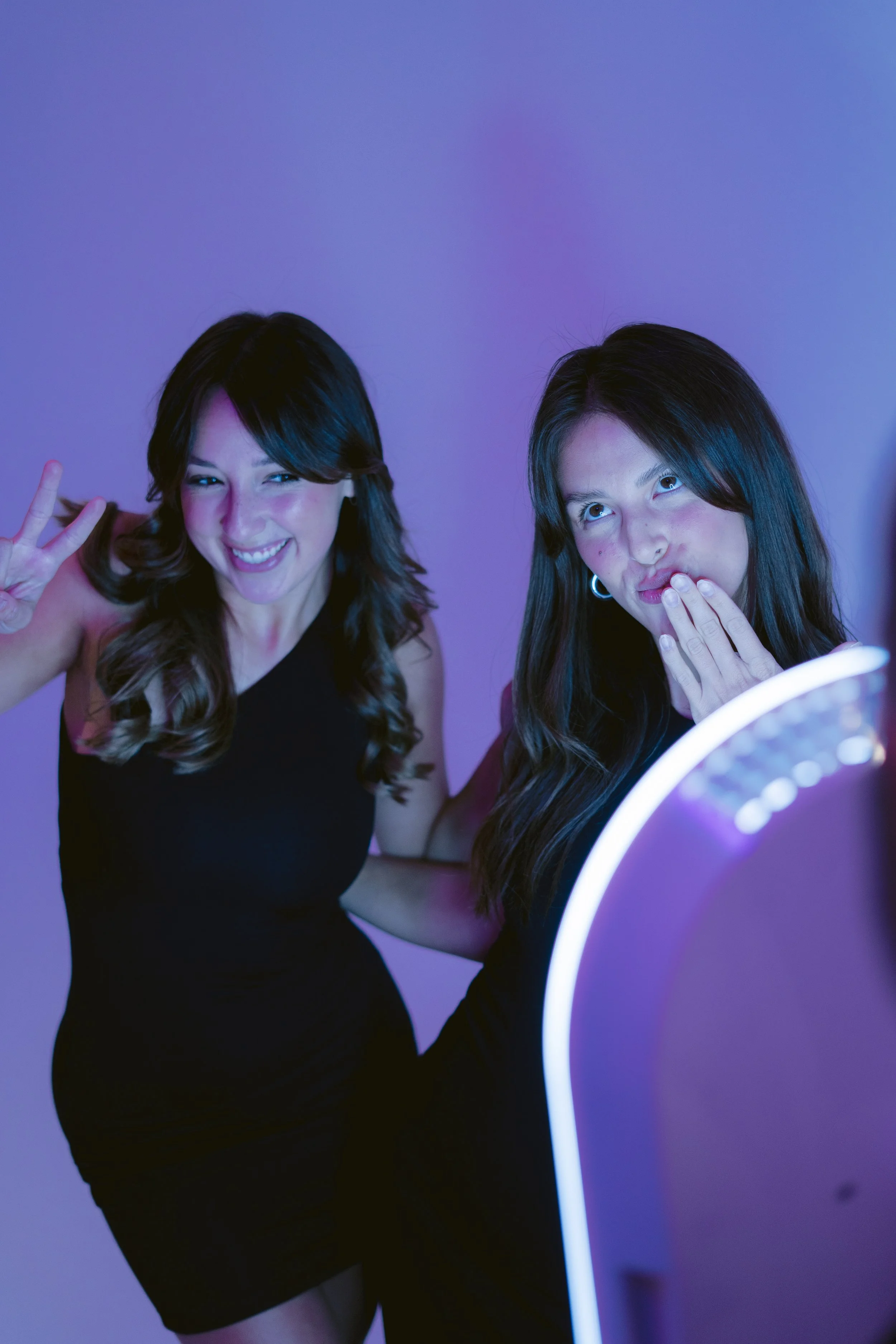 Two girls posing in front of roaming photobooth with happy smiles at a social event