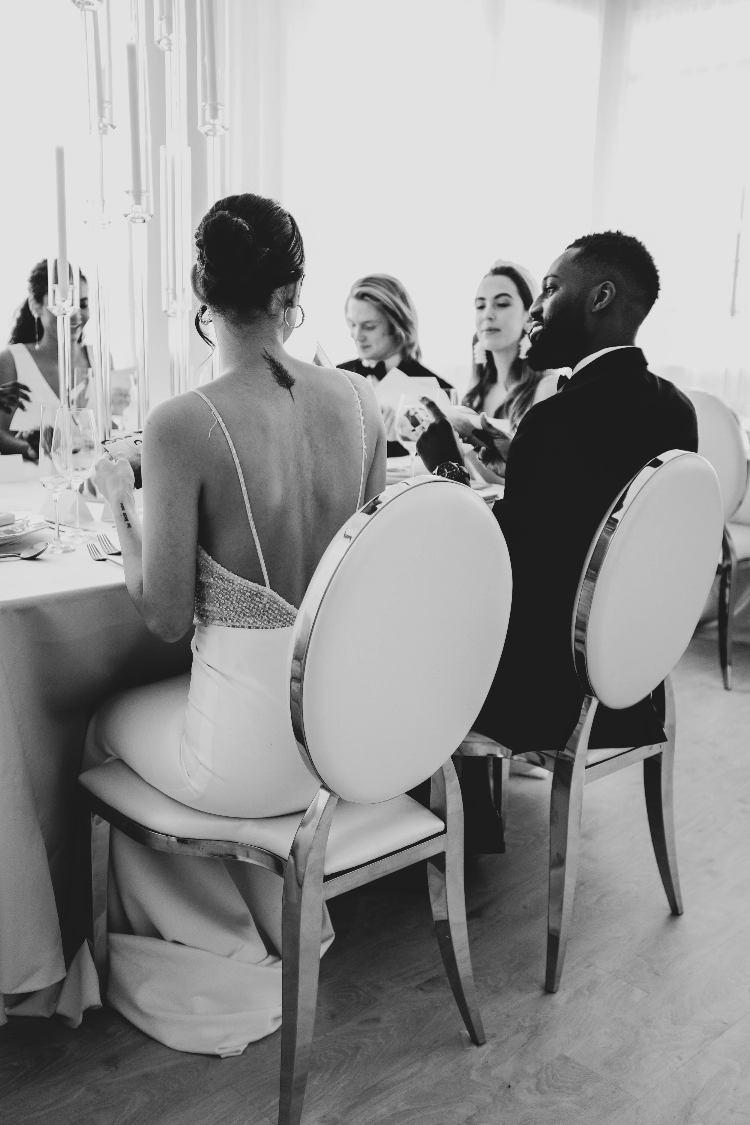 Group of people at a dinner table wearing formal clothes and discussing their photos