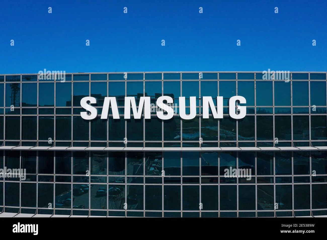 Modern building with large Samsung logo on glass facade against clear blue sky.