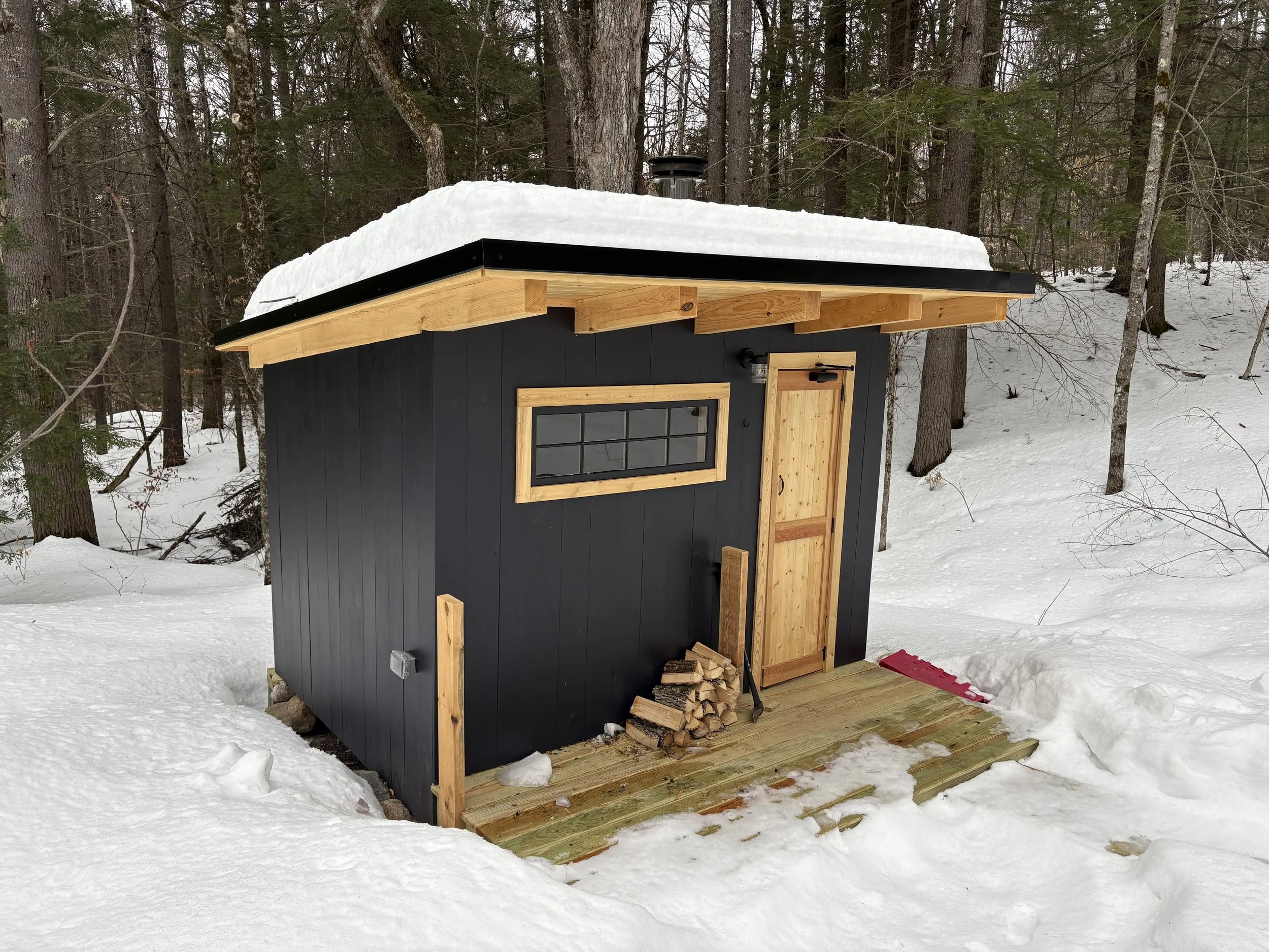 Small black and wood Sauna house in snowy forest built by Silas Miller Stove & Chimney