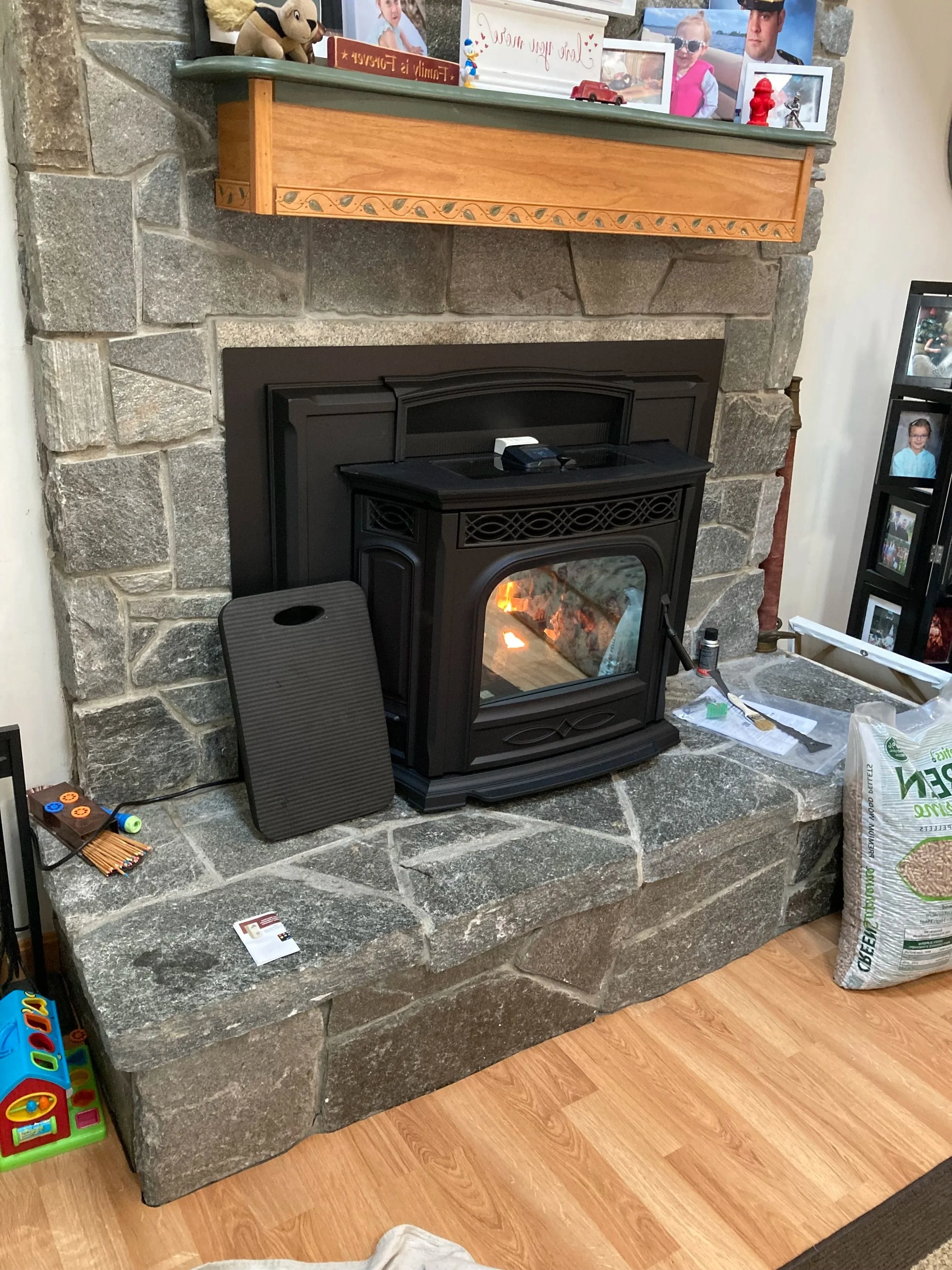 A stone fireplace with a black harman pellet insert burning fire. installation just completed by Silas Miller Stove & Chimney