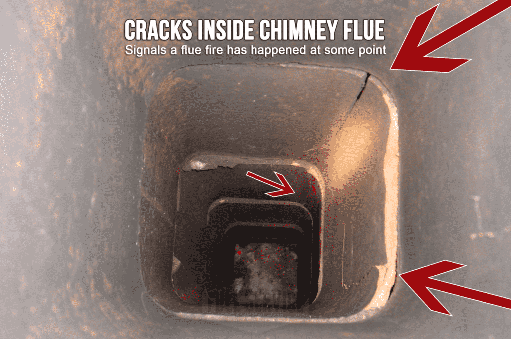 Close-up view of the inside of a chimney flue showing cracks with arrows pointing to them, indicating a fire has occurred inside at some point.