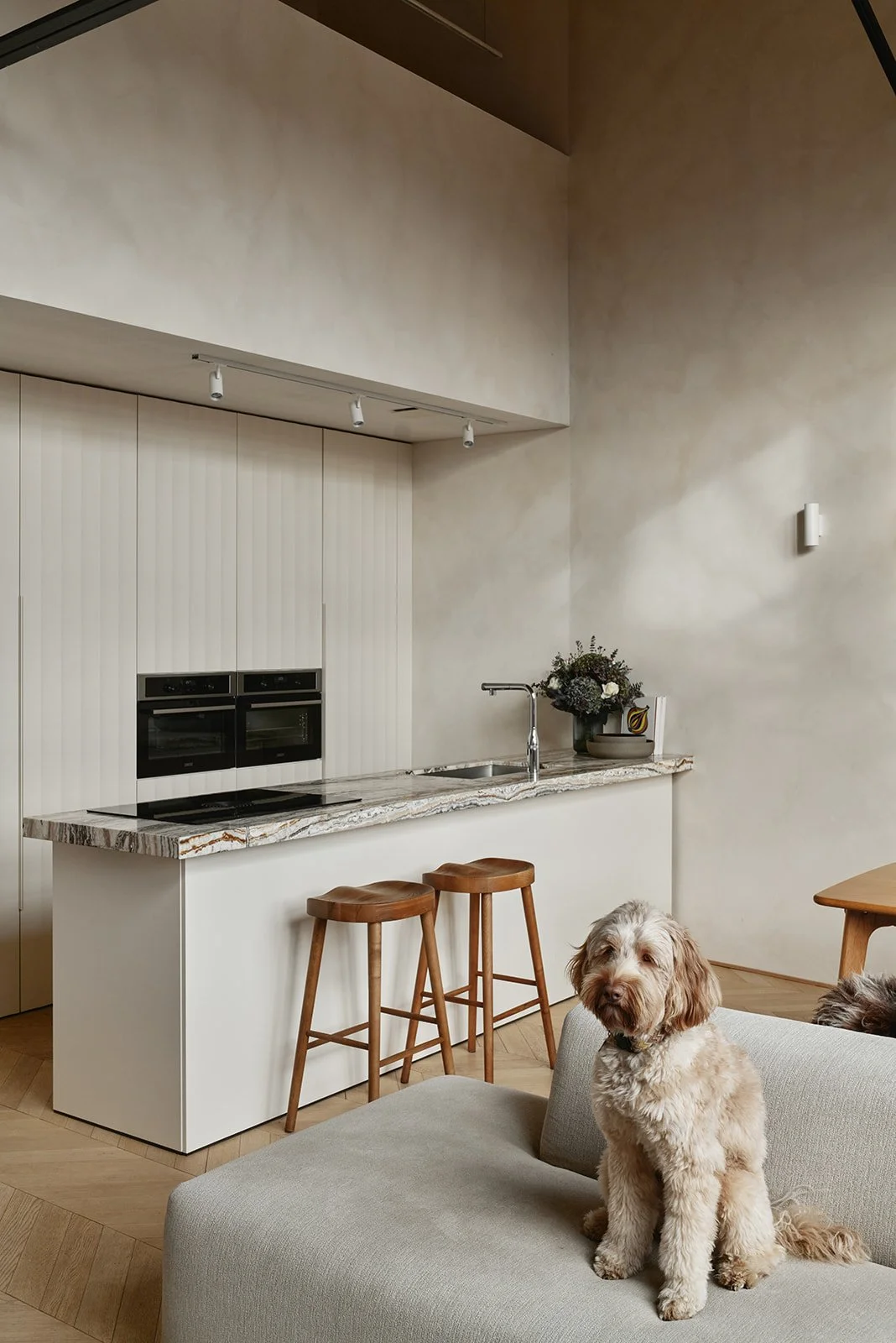 Leefruimte met keuken en maatwerk eiland in natuurlijke materialen en warme afwerking.