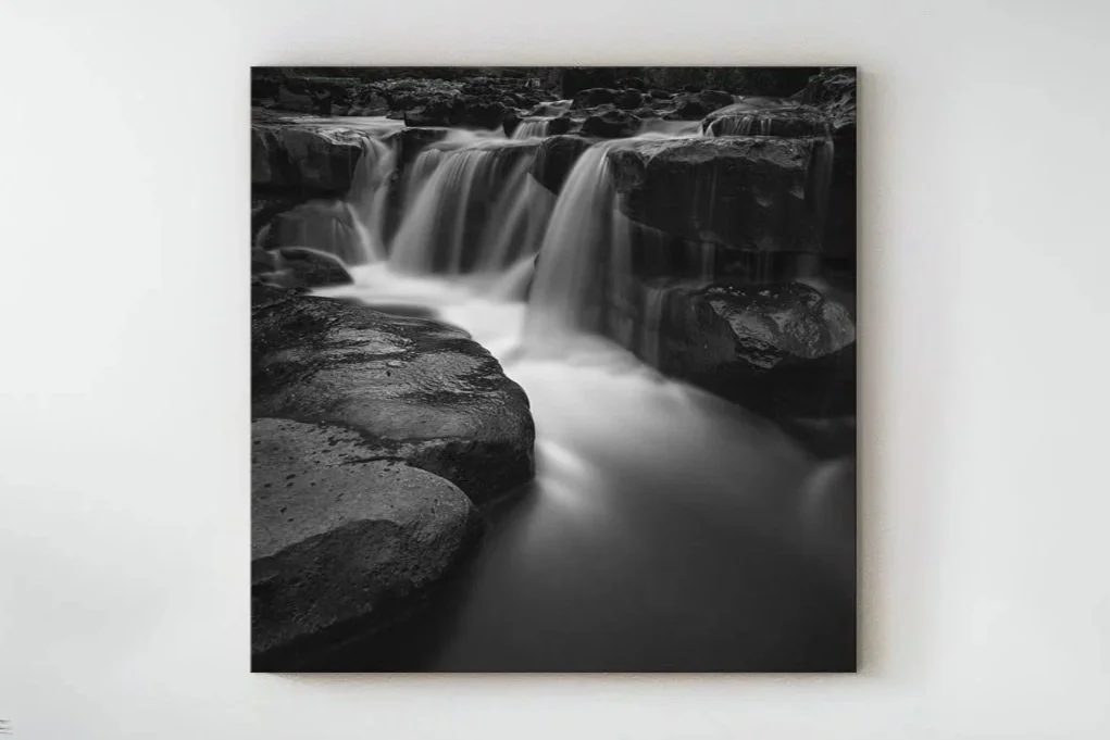 Black and white photograph of waterfalls over rocky terrain