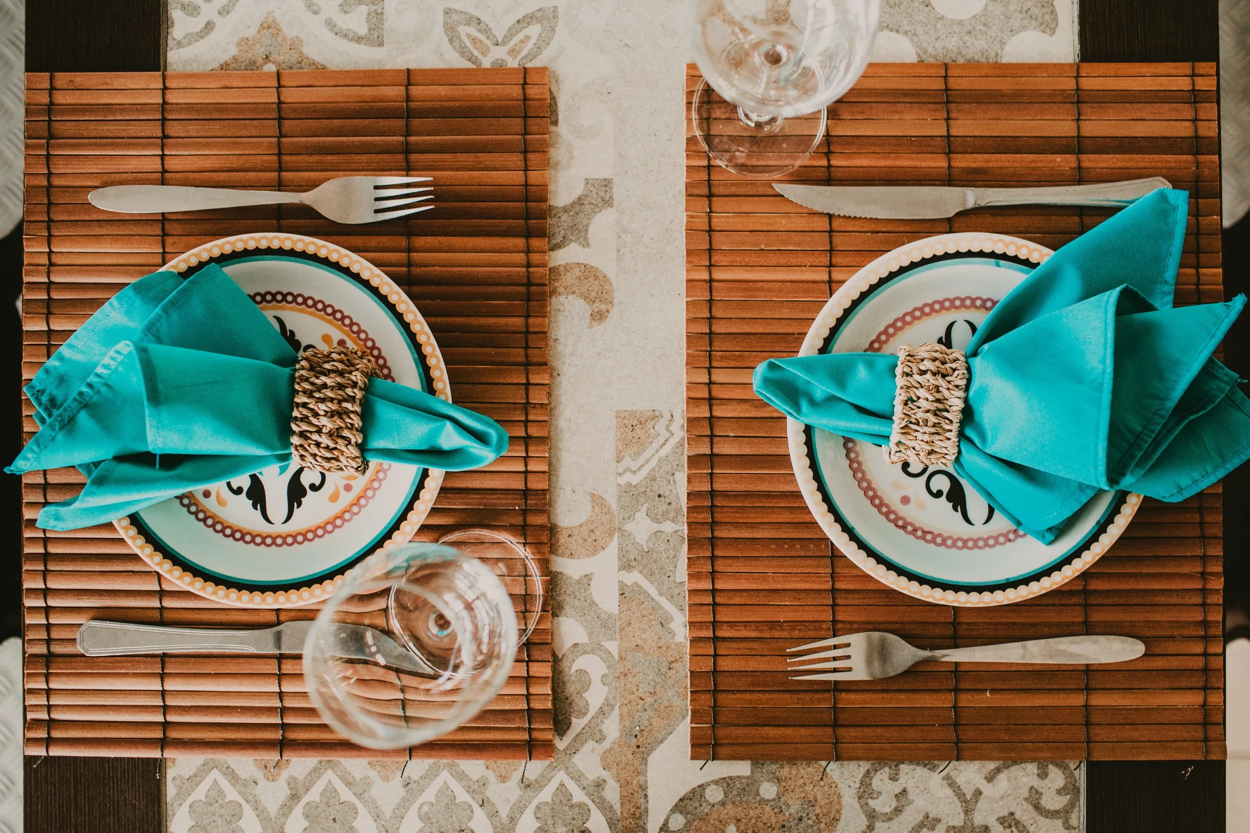 Table set for two people with bamboo mats, colourful tableware and turquoise napkins