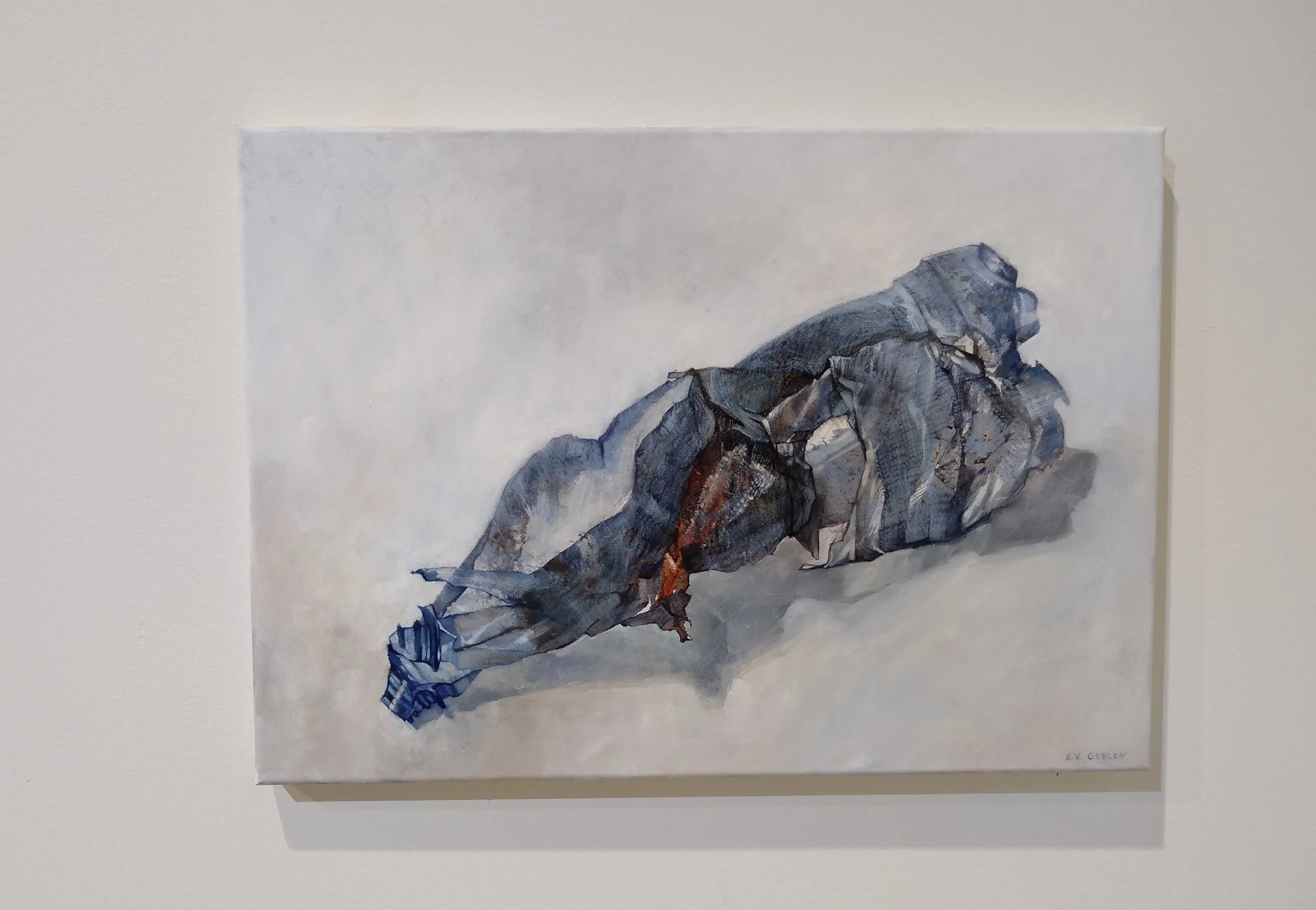 Watercolor painting of crumpled, pleated fabric with shades of blue, gray, and brown, resting on a light background.