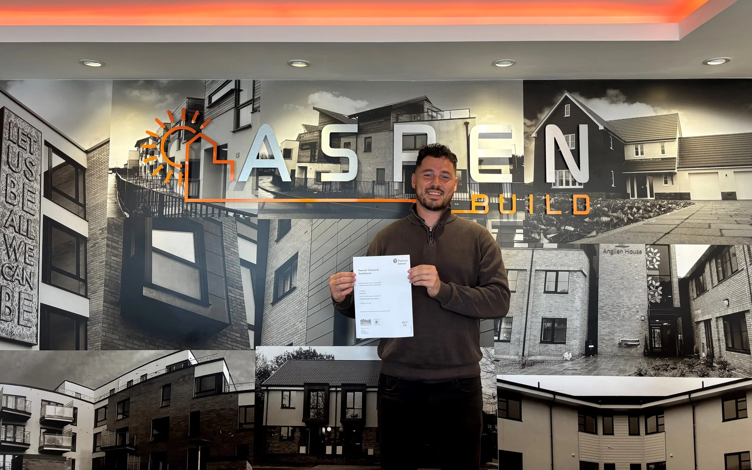 Jake Betts holding his NVQ Level 7 certificate at Aspen Build