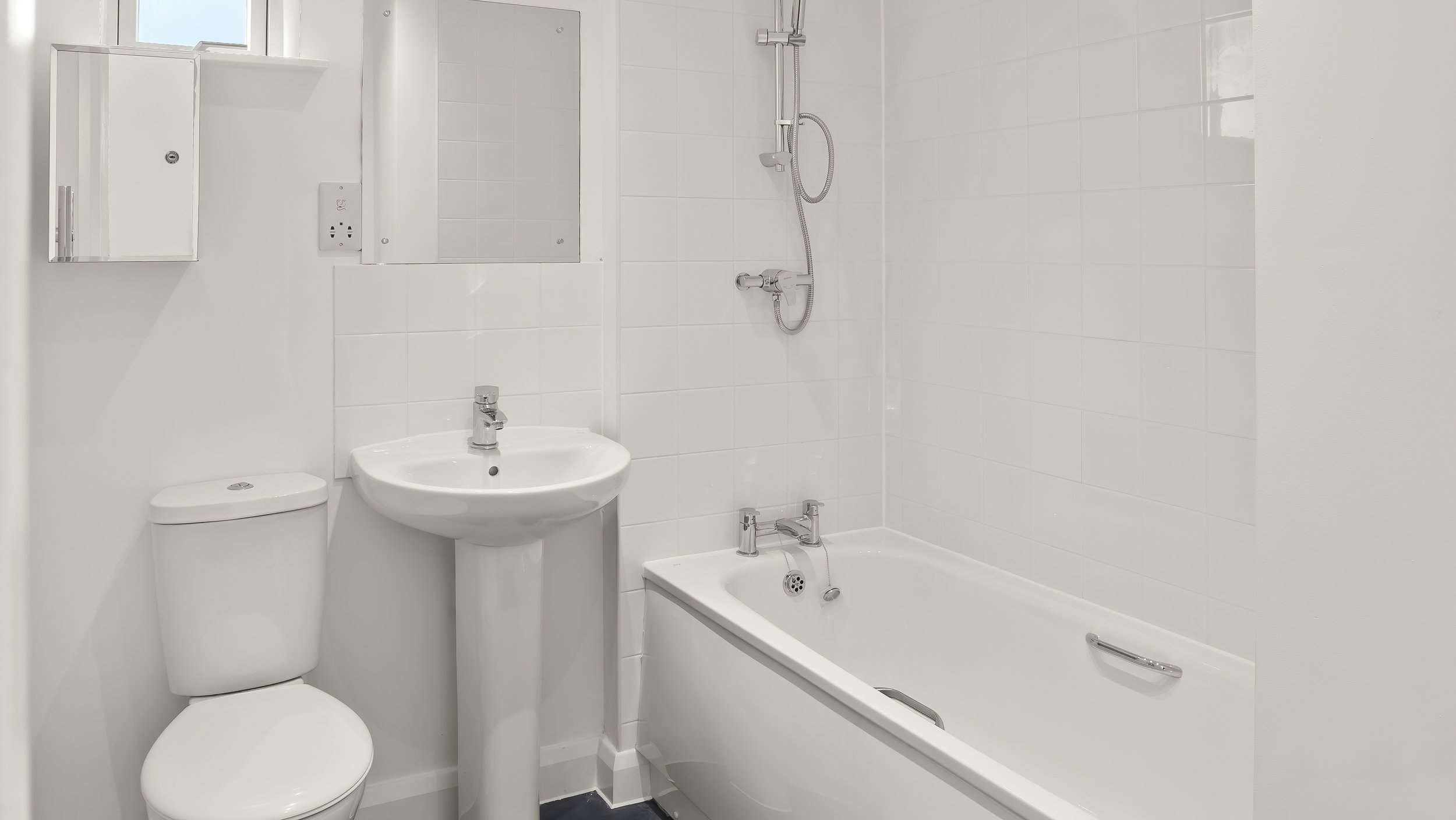White bathroom with bath and shower at Loxford Hall