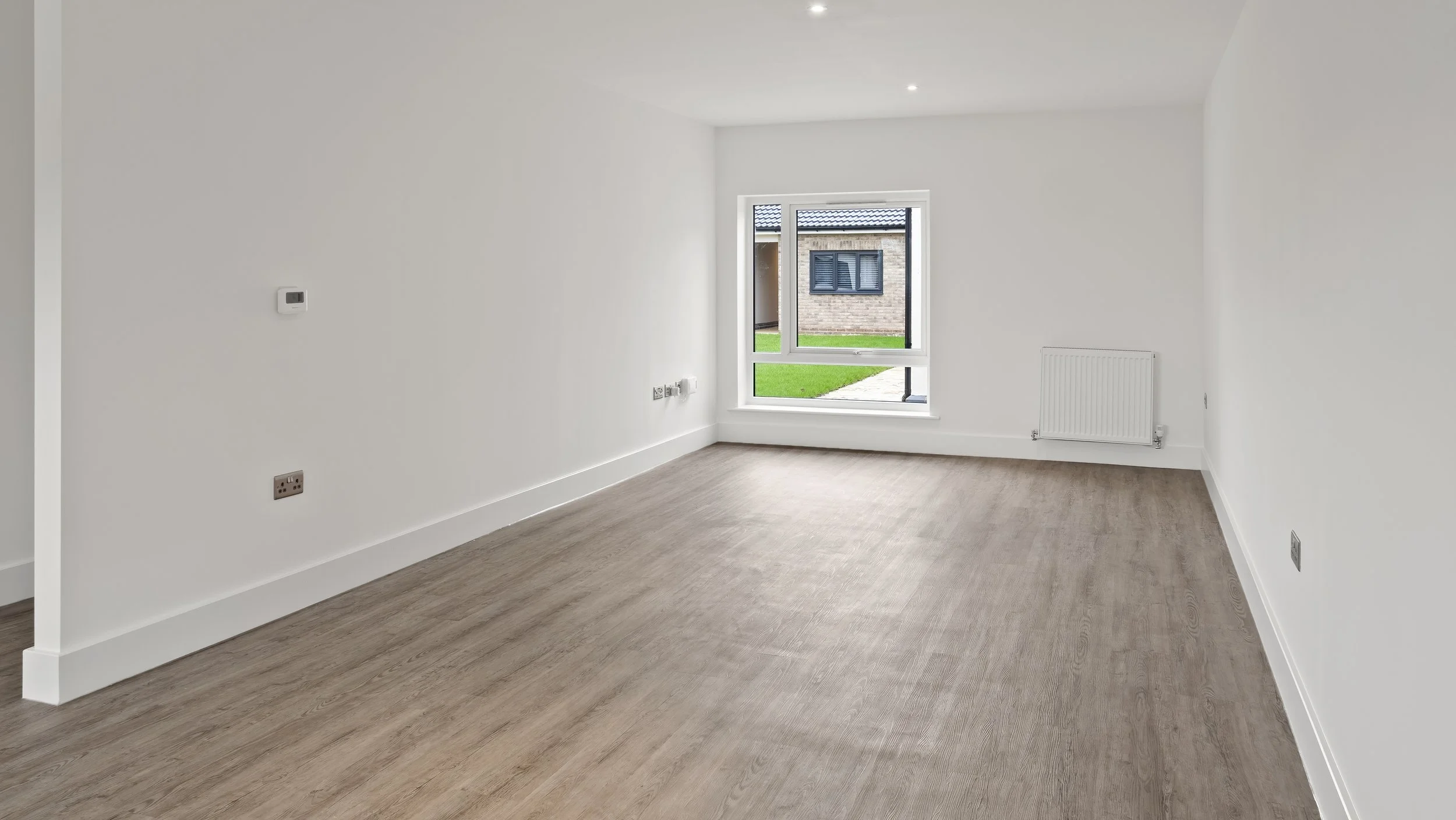 Open-plan unfurnished room with wood-effect flooring at Wamil Court