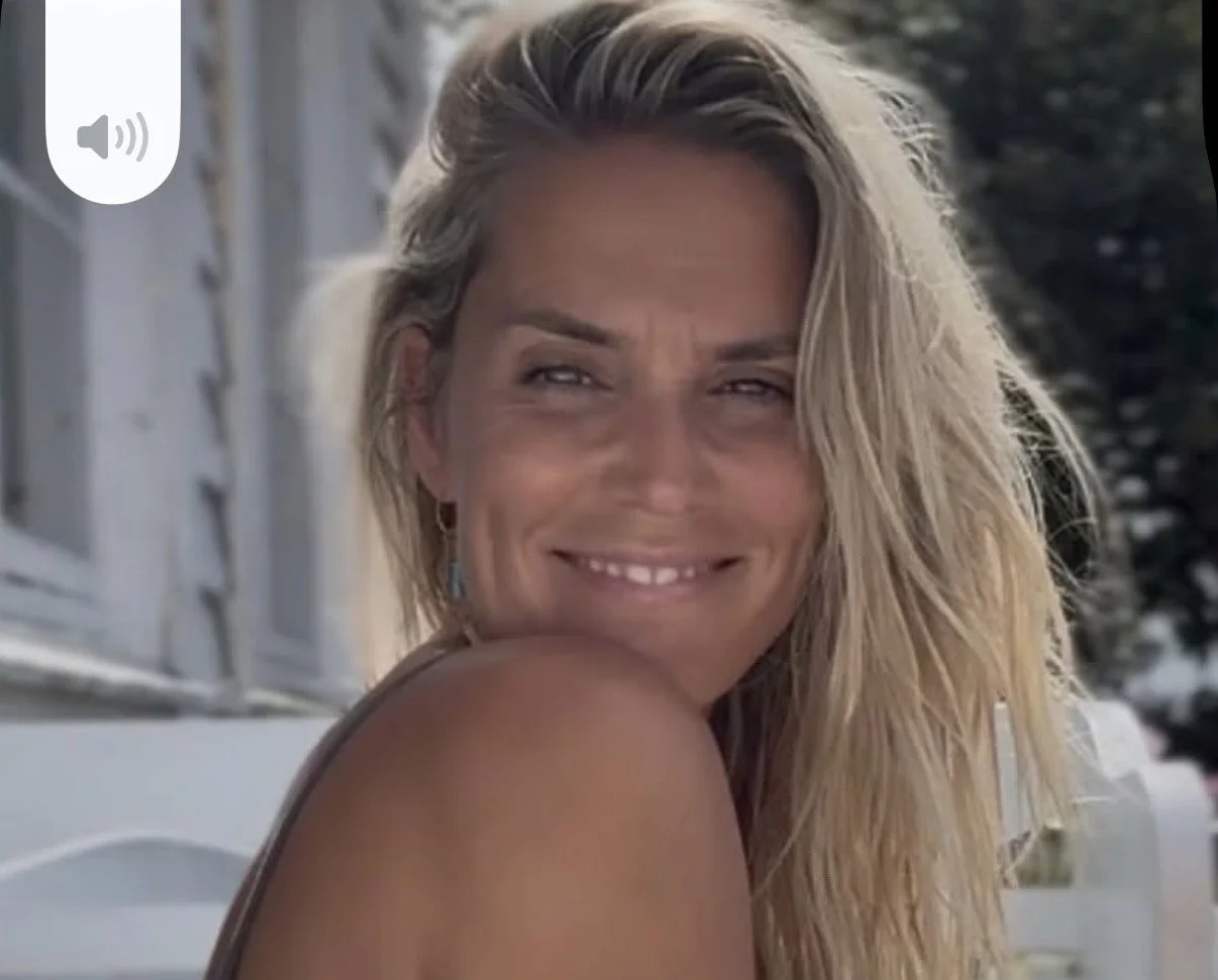 Et nærbilde av en smilende kvinne med langt, blondt, vått hår, som ser ut til å nyte solen.