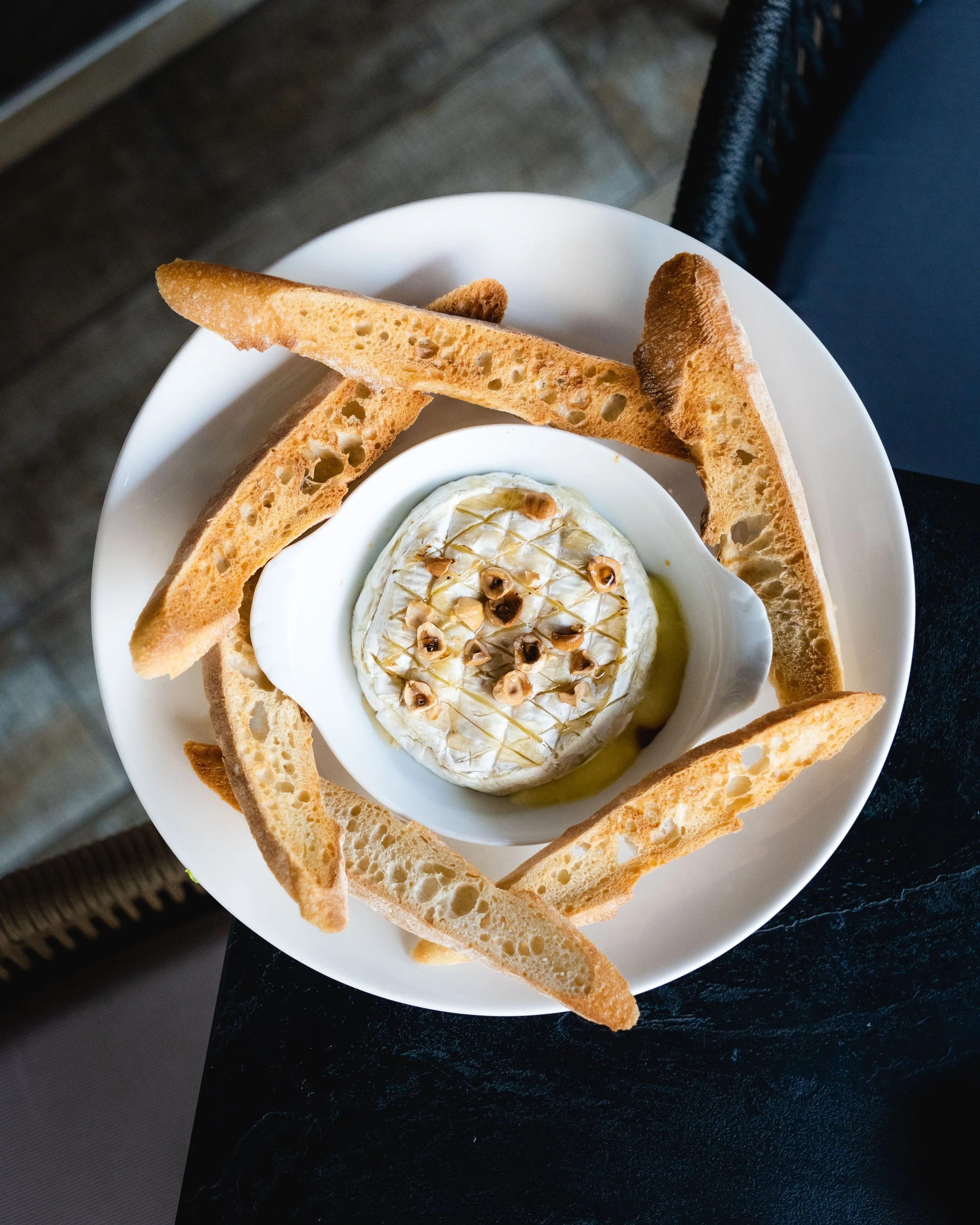 Assiette de nourriture variée comprenant des tranches de jambon, des olives, du houmous avec des morceaux de légumes, des rondelles d'oignons frits, du guacamole, du pain pita coupé en triangles, des chips, des sauces, au garden Ice