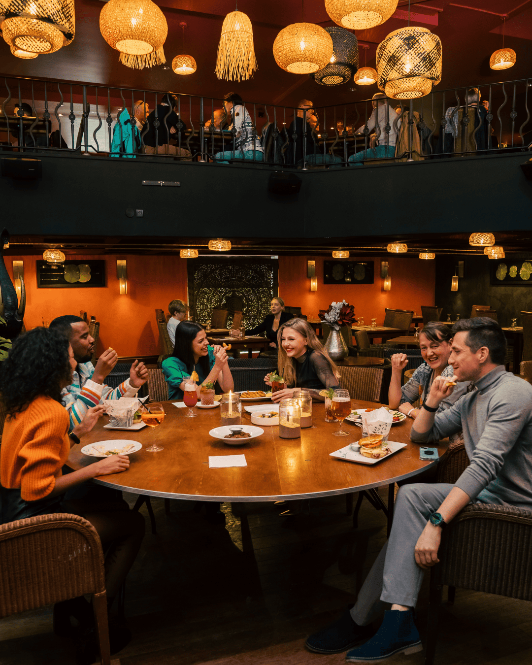 Groupe de jeunes adultes riant et discutant autour d'un repas au Garden Ice Café
