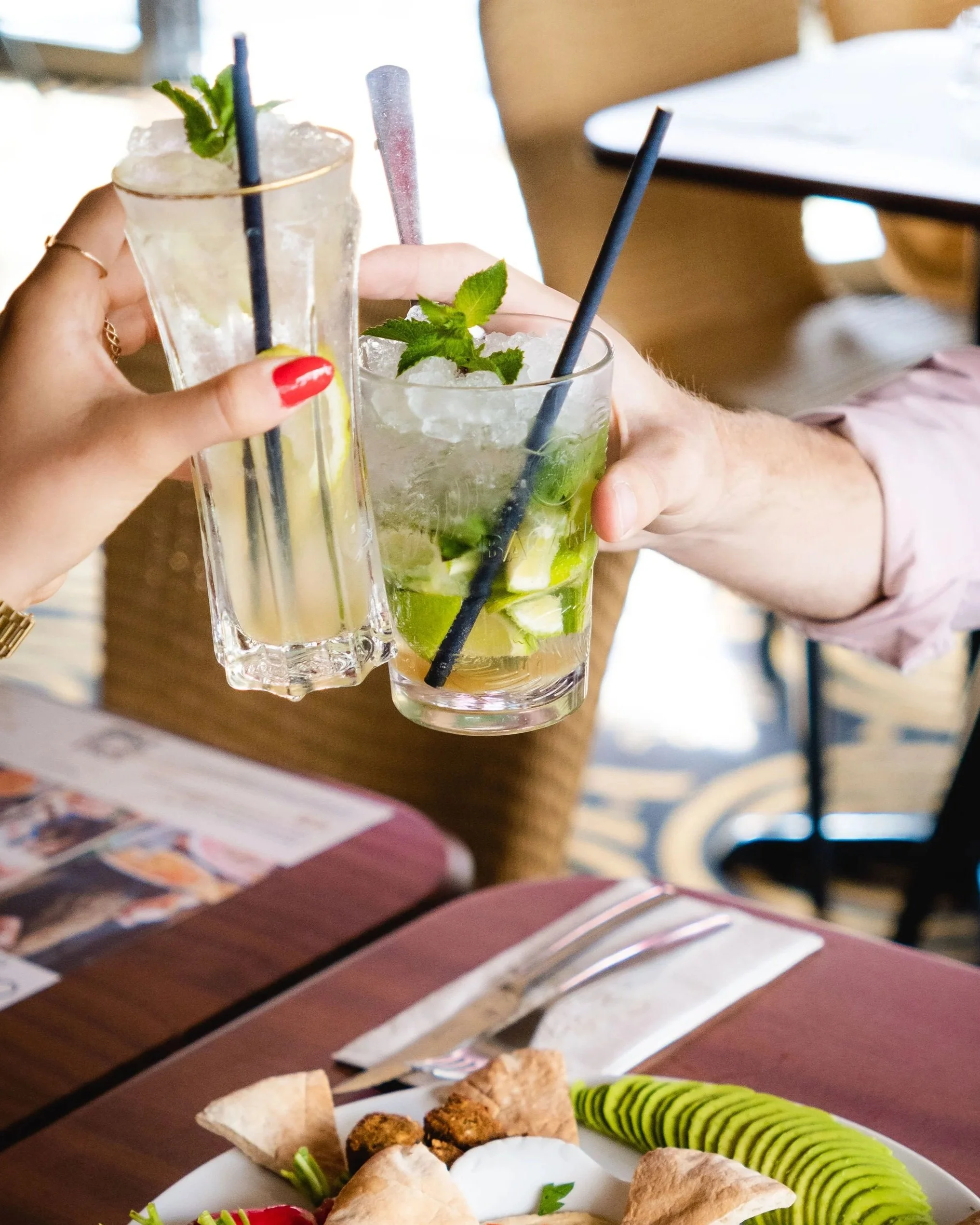 Deux femmes souriantes, partageant un repas dans un restaurant avec un plateau de charcuterie et un verre au Garden Ice