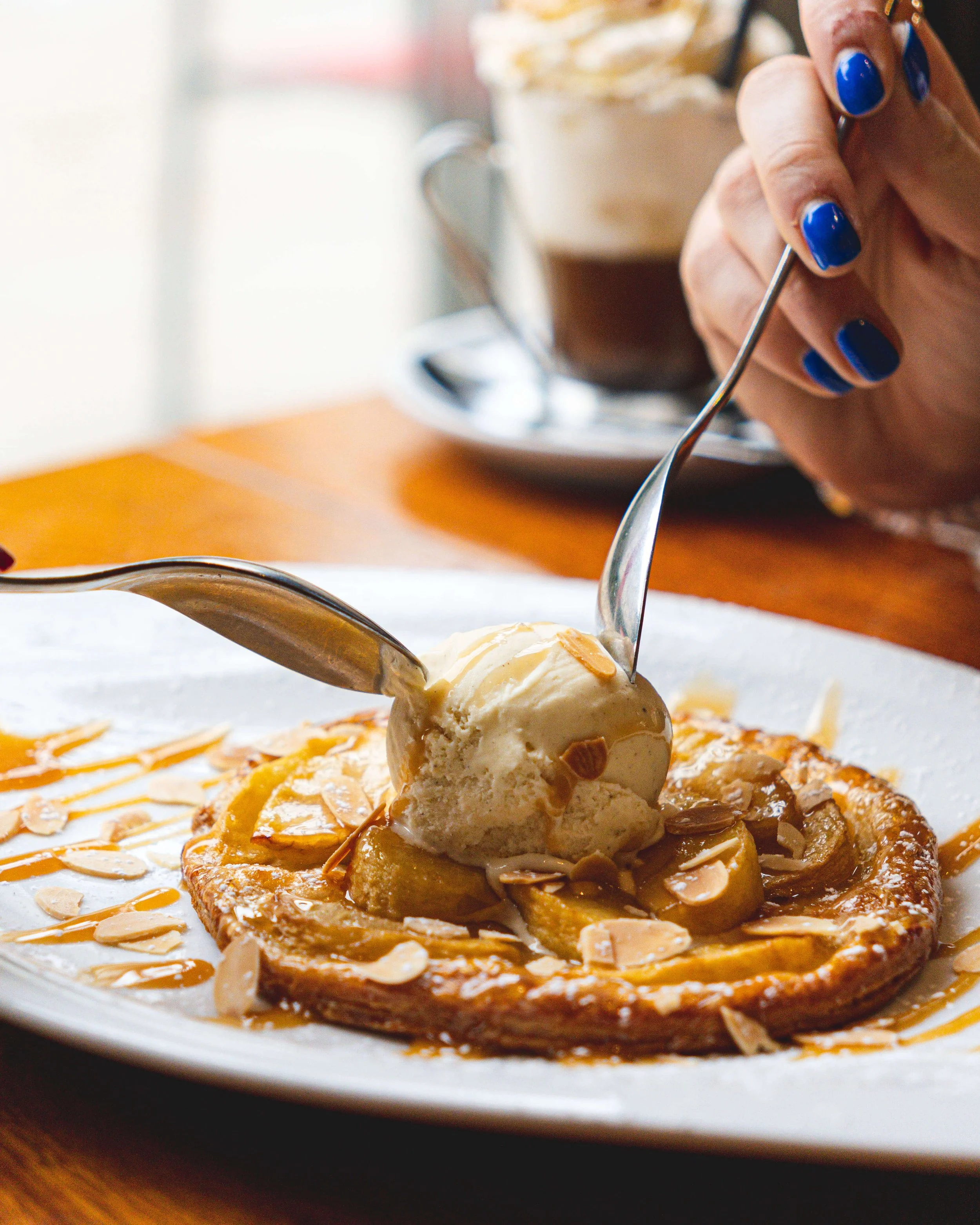Une tarte aux pommes avec une boule de glace à la vanille, saupoudrée d'amandes effilées et de caramel, sur une assiette blanche au Garden Ice