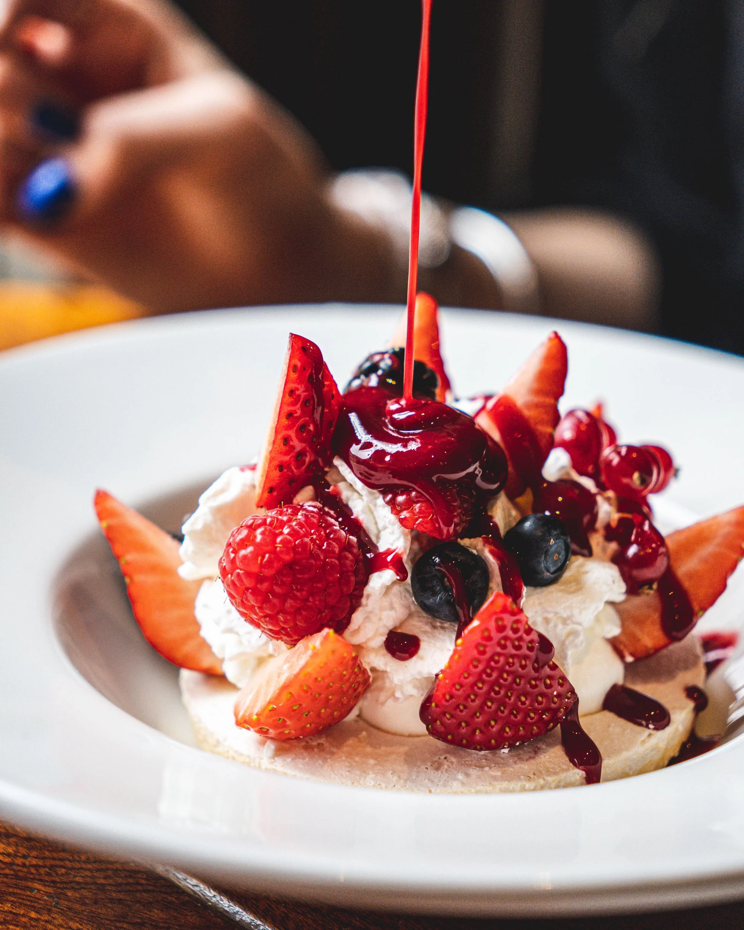 Gâteau de fruits avec des fraises, des framboises, des myrtilles et de la crème, avec du sirop rouge en train d'être versé au Garden Ice
