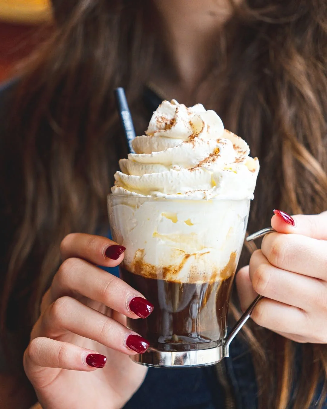 Une femme tient un verre de crème glacée ou de café glacé avec de la crème fouettée et de la poudre de cacao au garden Ice