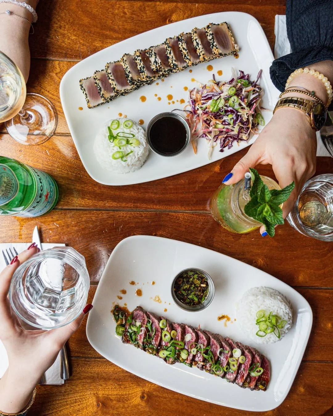 Deux plats de poissons et de viande, accompagnés de riz et de salade, servis sur des assiettes blanches sur une table en bois, au Garden Ice Café