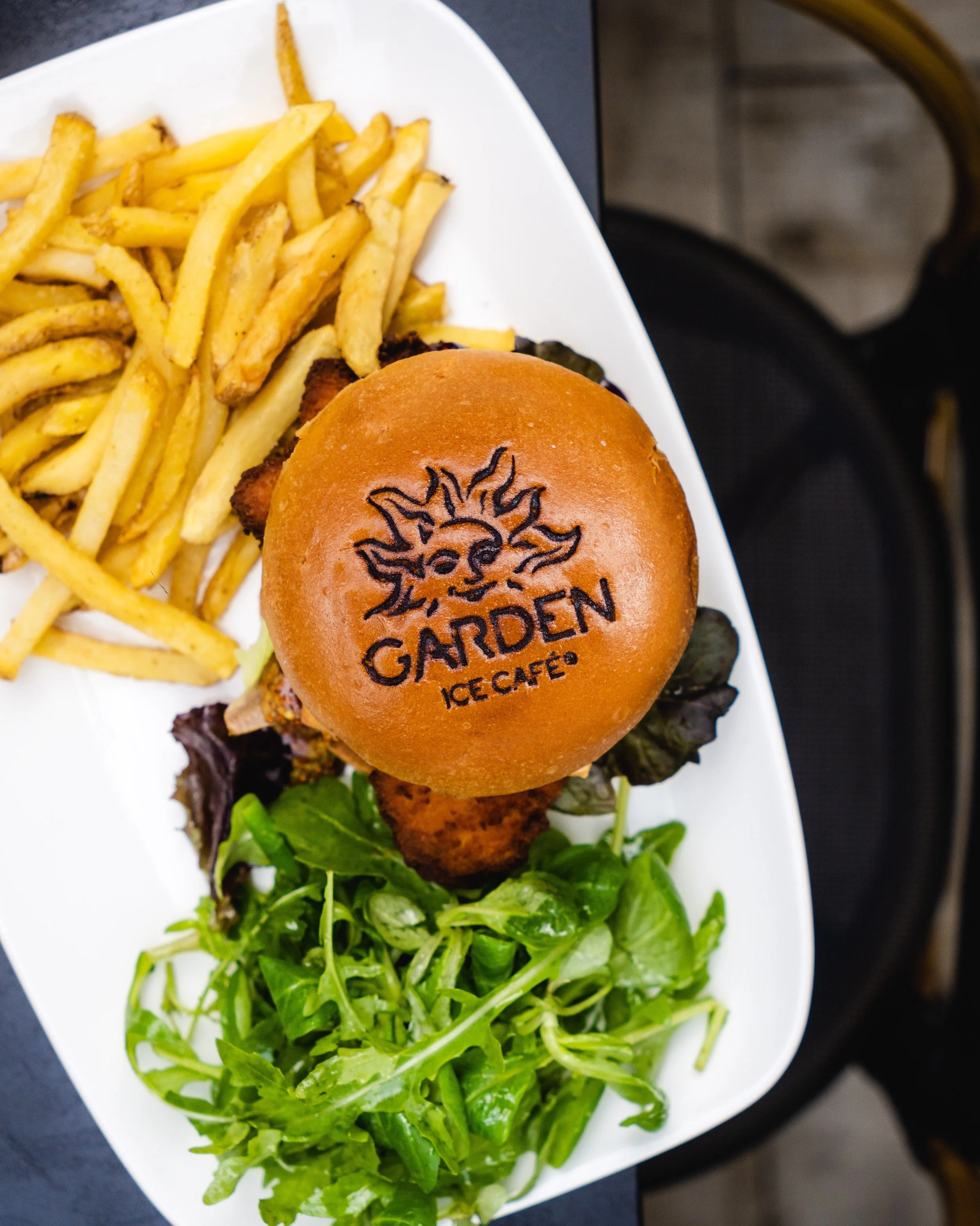 Un sandwich au poulet frit avec du fromage et de la confiture, accompagné de pommes de terre frites et une salade, au Garden Ice Café 